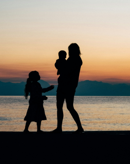 A moth with two children with the sea view in the background A moth with two children with the sea view in the background