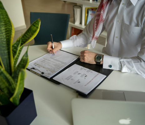 The person signing documents with a pen on papers placed on a table. The person signing documents with a pen on papers placed on a table.