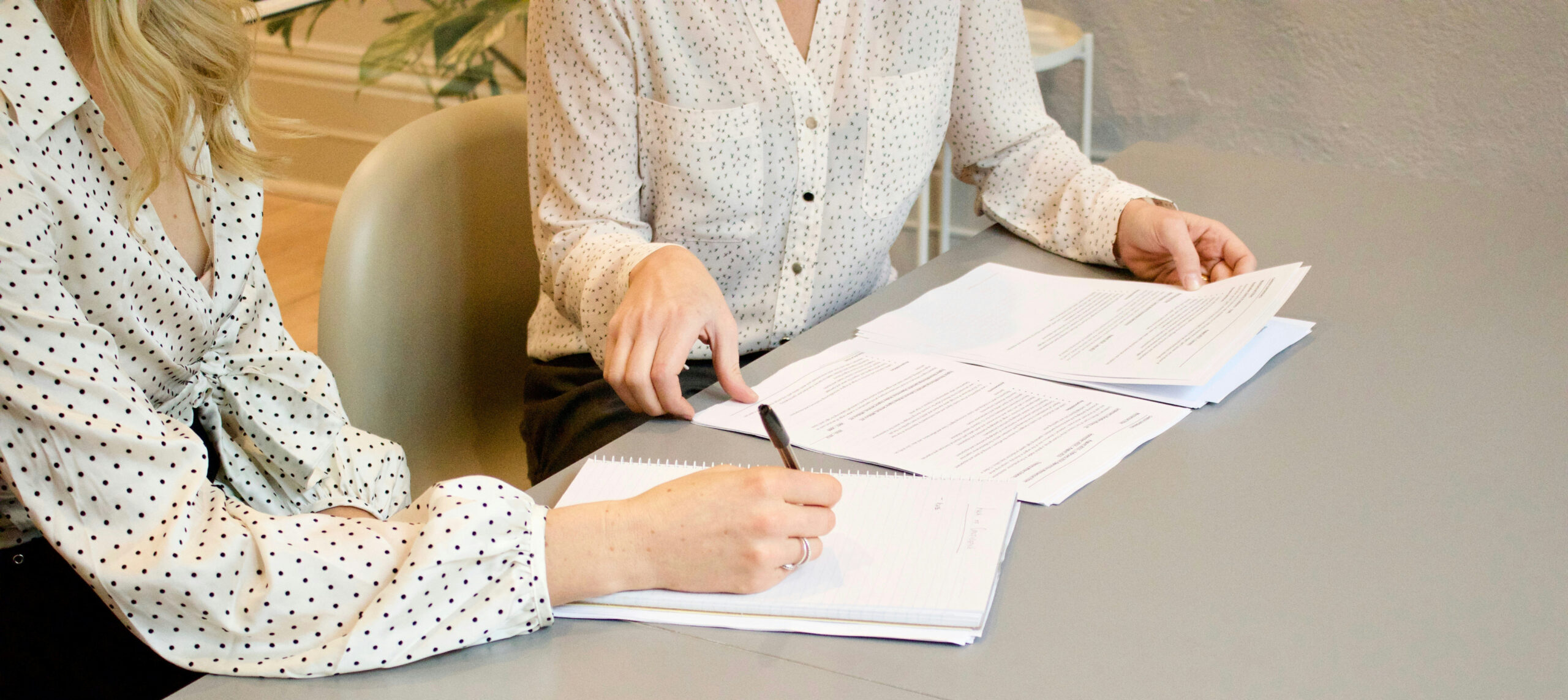 One person is holding documents while another person is making notes