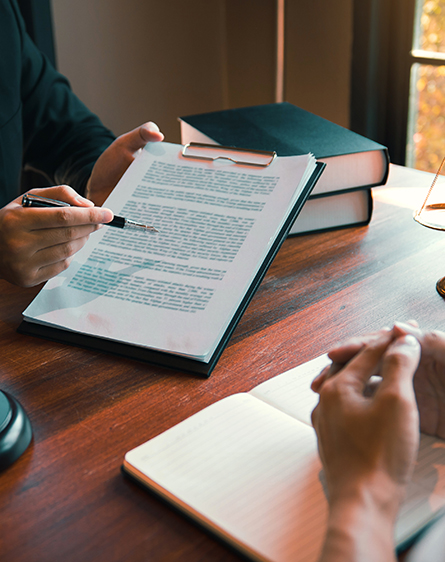 Person holding documents in hand and pointing to them with a pen