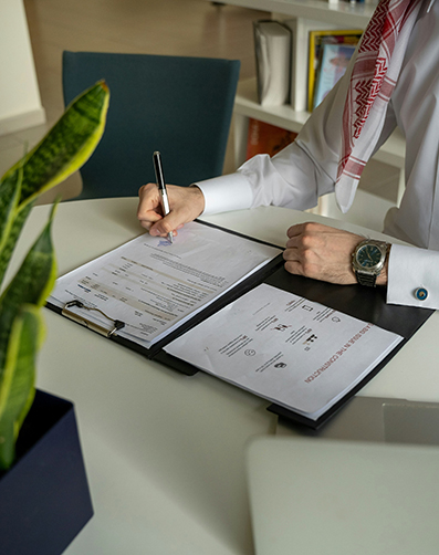 The person signing documents with a pen on papers placed on a table. The person signing documents with a pen on papers placed on a table.
