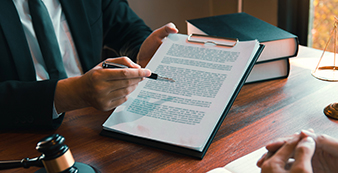 Person holding documents in hand and pointing to them with a pen